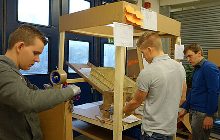 Drei Studierende bauen prototypischen Prüfstand aus Holzleisten und Pappe