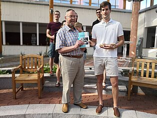 Bestleistung: Dozent Heinrich Schneider übergibt Buchpreis an Studierenden Georg Burkhardt