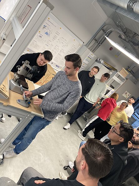 Studierende zeigen anderen die Arbeit an einem Messarbeitsplatz